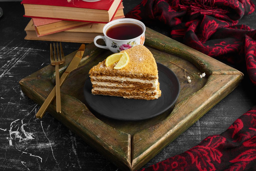 A slice of medovic cake with lemon and tea